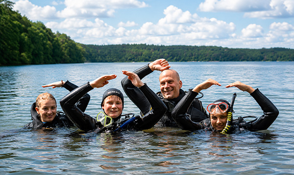 Zwei Jugendliche beim Tauchen mit einem erwachsenen Tauchlehrer in einem See